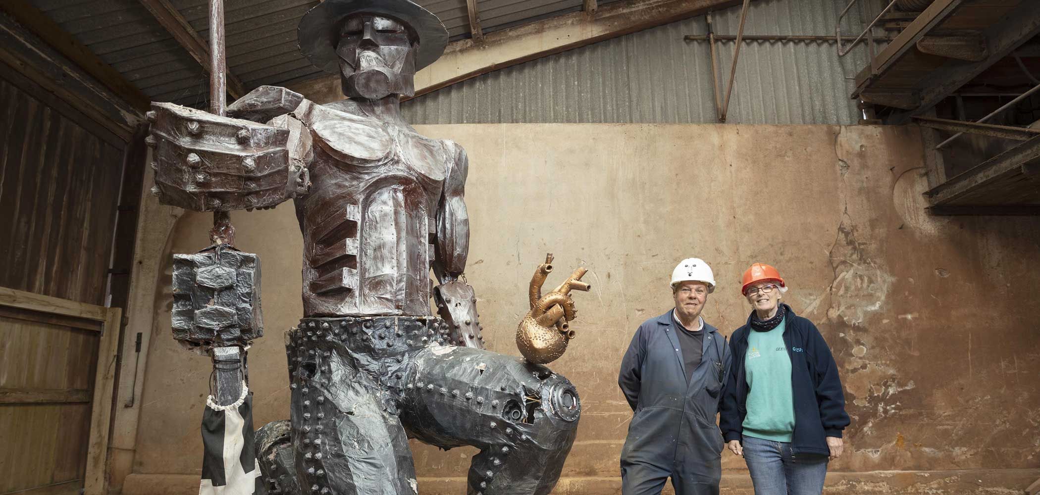John Wright and Geevor Tin Mine colleague standing next to statue of a miner made from tin